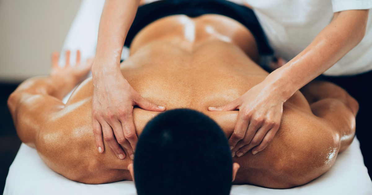 A therapist giving a firm oil back massage on fresh white sheets during a late-night massage in Bangkok