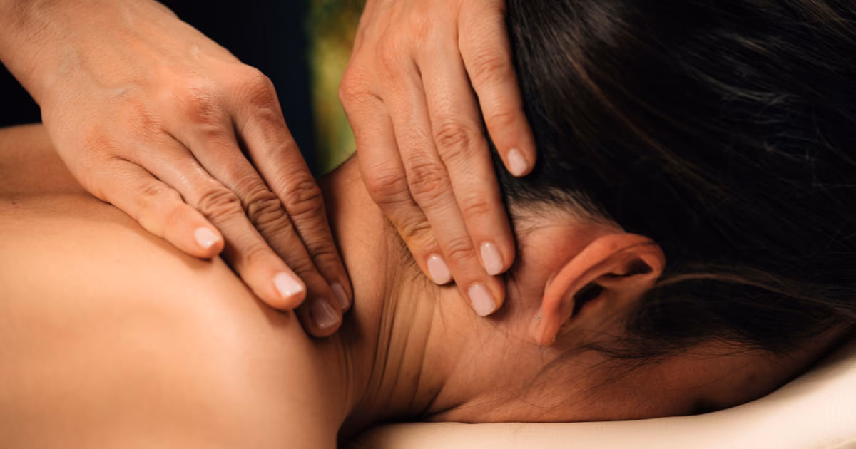 A therapist working the neck, shoulders, and base of the skull with both hands during a massage for tension headache in Bangkok