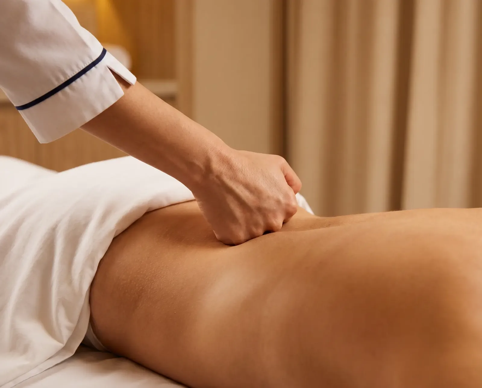 Close-up of a Luna therapist's knuckles pressing firmly into a client's lower back during a deep tissue massage